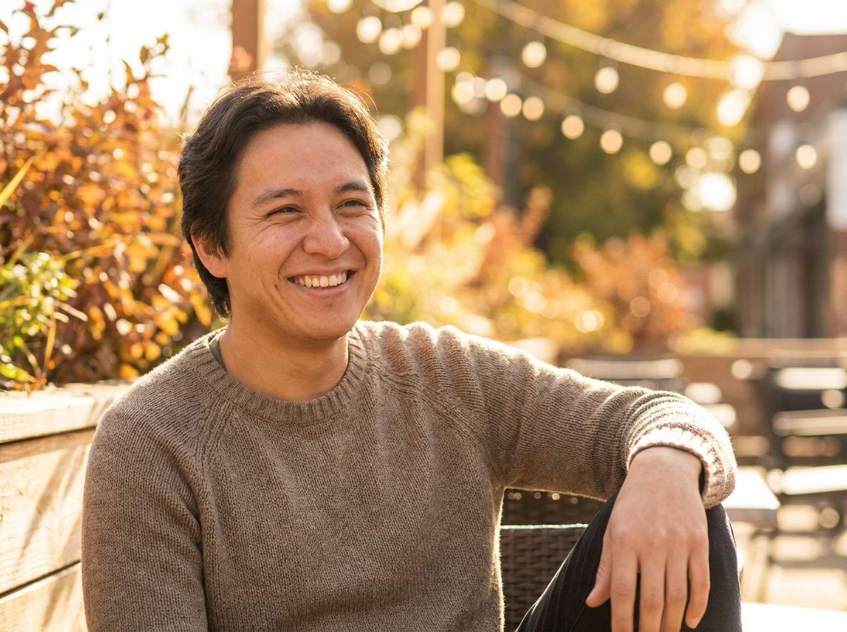A close-up of a person-s relaxed and genuine smile during a photoshoot, showing comfort and authenticity. The background is softly blurred, focusing on the subject-s expression.