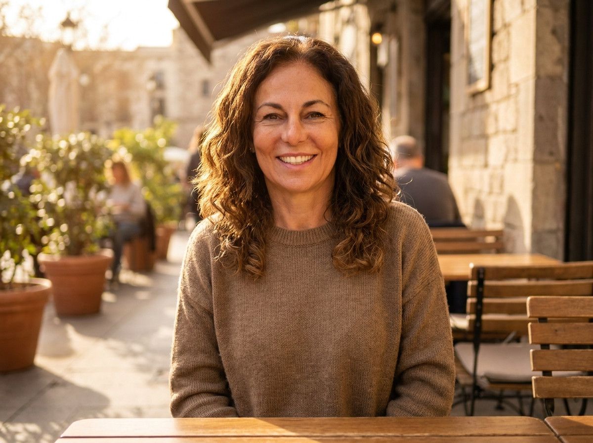 A close-up portrait of a woman with a confident, relaxed smile, her hair styled naturally and looking healthy. The focus is on her genuine emotion and comfort, not just her hair color.