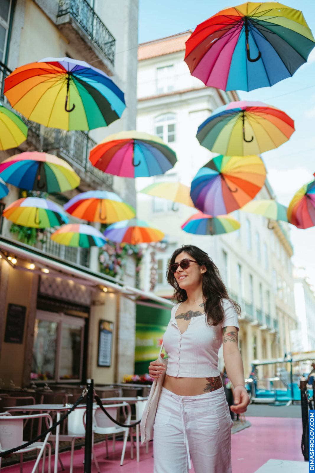 Woman walking under rainbow umbrellas in Lisbon, Portugal. Colorful street scene. Lisbon vibes.