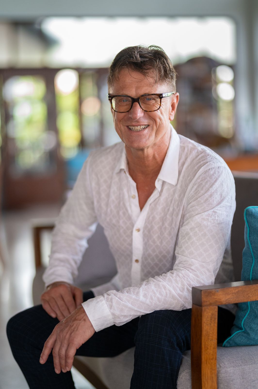 Man in Lisbon. Portrait of a smiling man with glasses, seated indoors. Lisbon vibes.