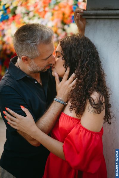 Romantic couple kissing in Lisbon, Portugal. Colorful flowers in background. Intimate moment, travel photography.
