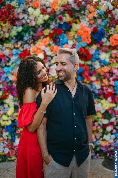 Couple in Lisbon, Portugal, posing in front of a vibrant flower wall. Romantic moment, travel photography.