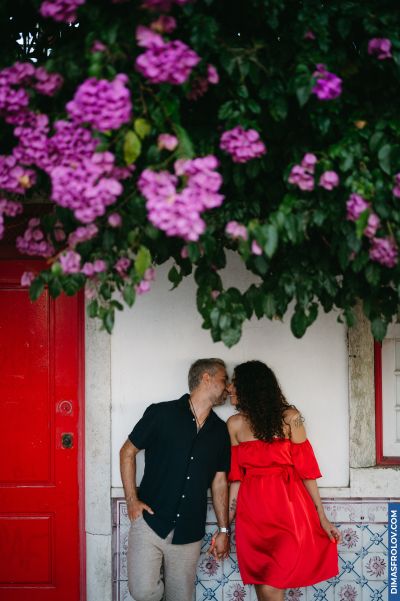 Couple kissing in Lisbon, Portugal. Traditional tiles, red door, and vibrant bougainvillea flowers create a romantic Alfama scene.