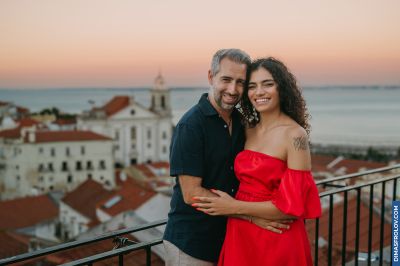 Couple in Lisbon, Portugal. Red rooftops & Tagus River backdrop. Romantic moment in Alfama at sunset. Travel photography.