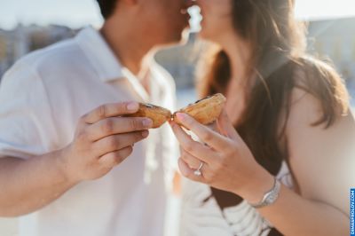Couple kissing over a Pastel de Nata in Lisbon, Portugal. Engagement ring visible. Romantic travel.
