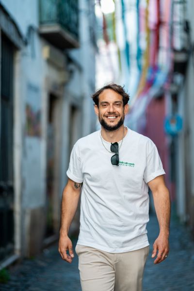 Smiling man on a Lisbon street. Colorful banners above. Alfama vibes. Portugal travel.