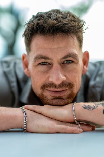 Portrait of a man in Lisbon, Portugal. Close-up with a blurred background. Tattooed arms and bracelets.