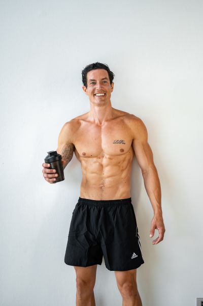 Shirtless man in Lisbon, Portugal, holding a protein shaker. Fitness in Portugal.