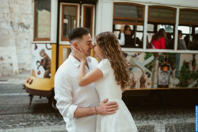 Couple embracing in Lisbon, Portugal, with a vintage tram in the background. Romantic moment in Alfama.