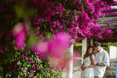 Couple in Lisbon, Portugal, under vibrant bougainvillea. Romantic moment, white clothing, sunny day. Lisbon atmosphere.