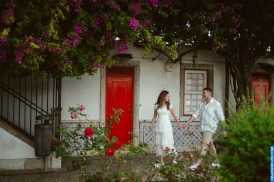 Couple strolling hand-in-hand in Lisbon, Portugal. Red door, flowering trees, and traditional tiles create a romantic atmosphere.