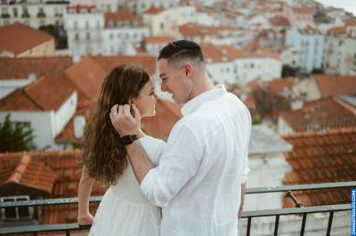 Romantic couple in Lisbon, Portugal. Red rooftops and cityscape backdrop. Love in Alfama.
