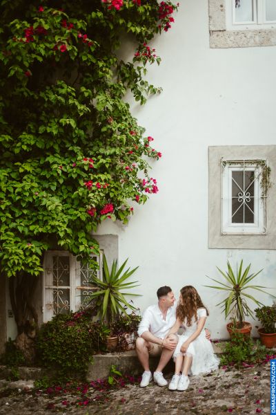 Couple in Lisbon, Portugal. Romantic moment by a white building with bougainvillea. Alfama vibes.