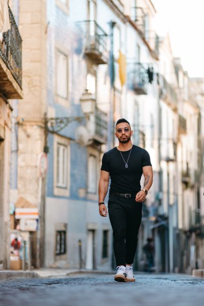 Stylish man walks Lisbon street. Alfama architecture, blue tiles, and cobblestone create classic Portugal scene. Travel photography.