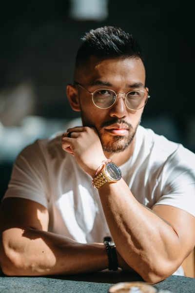 Stylish man with glasses in Lisbon cafe. Portrait with golden watch, sunny atmosphere. Lisbon vibes.