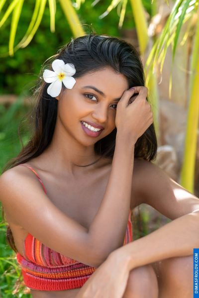 Woman with flower in hair, smiling. Tropical, lush background. Not Lisbon specific.