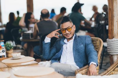 Stylish man in Lisbon cafe. Blue blazer, yellow glasses. Relaxed atmosphere, coastal vibe. Portugal travel.
